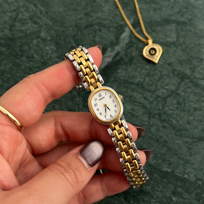 Woman holding a vintage two tone Seiko gold and silver ladies watch with a petite oval dial, styled against a green marble background with gold jewellery, vintage women’s watch available at The Gilded Hour NZ.