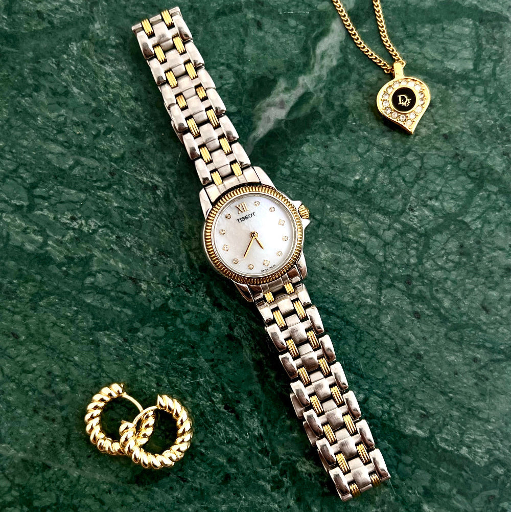 Vintage Tissot two tone ladies bracelet watch styled with gold jewellery on green marble, curated by The Gilded Hour NZ.