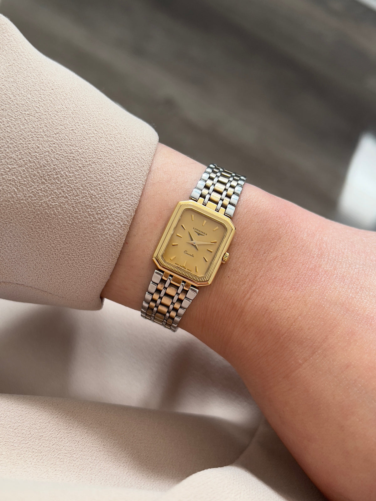 Longines gold and silver woman's watch nz on a wrist with a neutral background