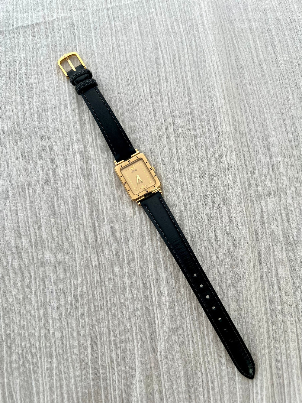 Seiko Black watch with gold case on a gray textured surface