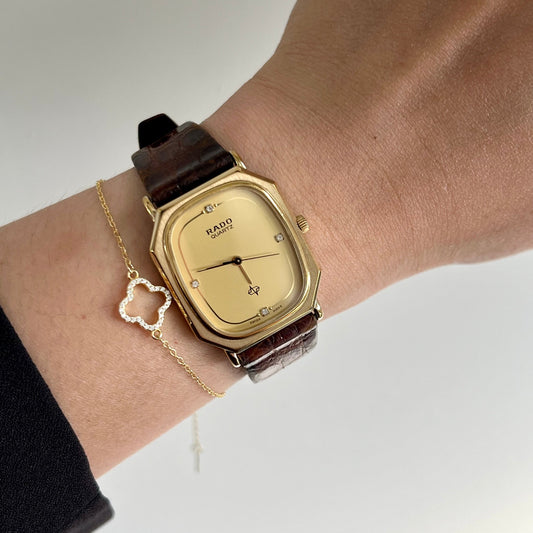 Gold Rado woman's watch with brown strap on wrist against a neutral background | The Gilded Hour collection New Zealand & Australia