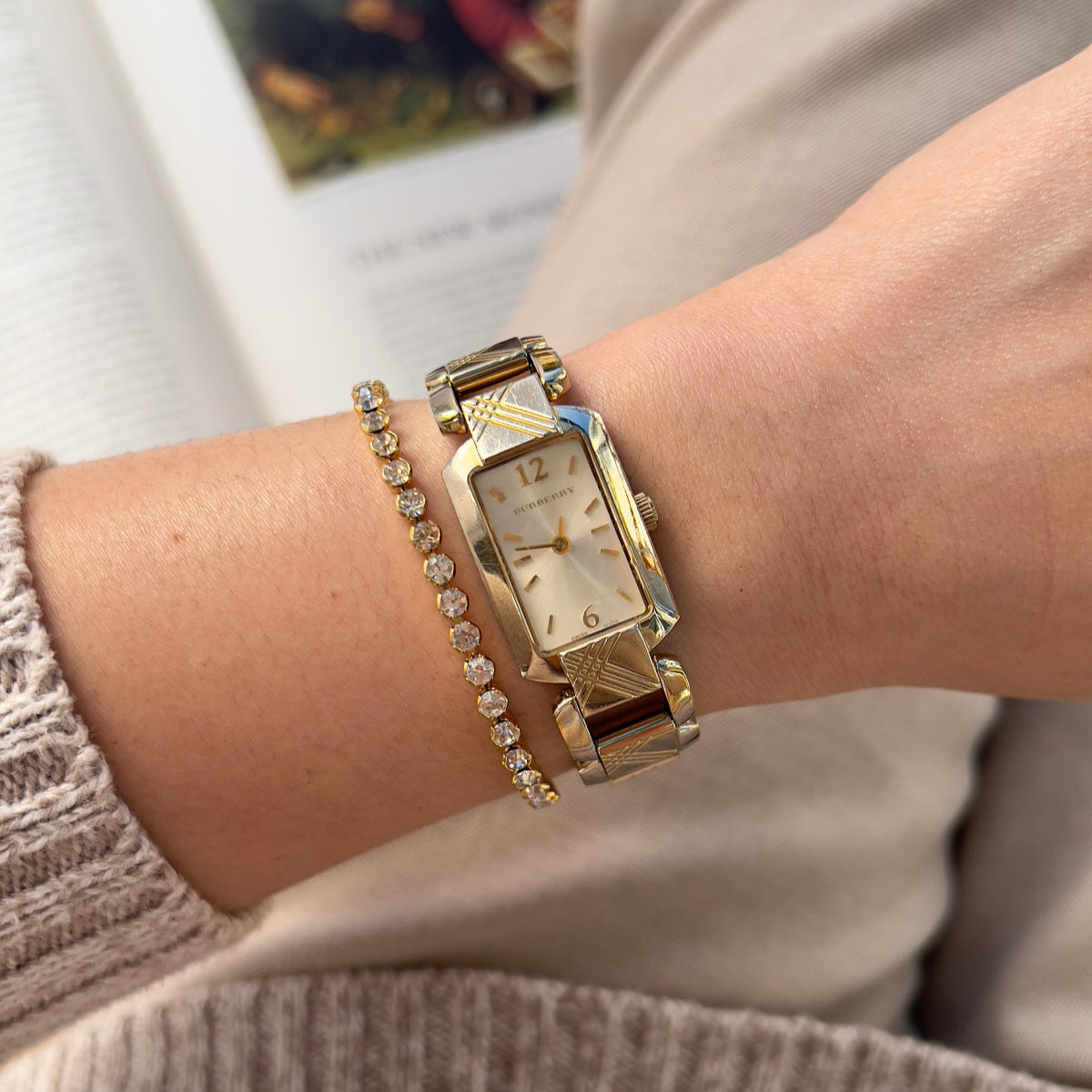 Gold Burberry tank watch with a linked bracelet worn on the wrist