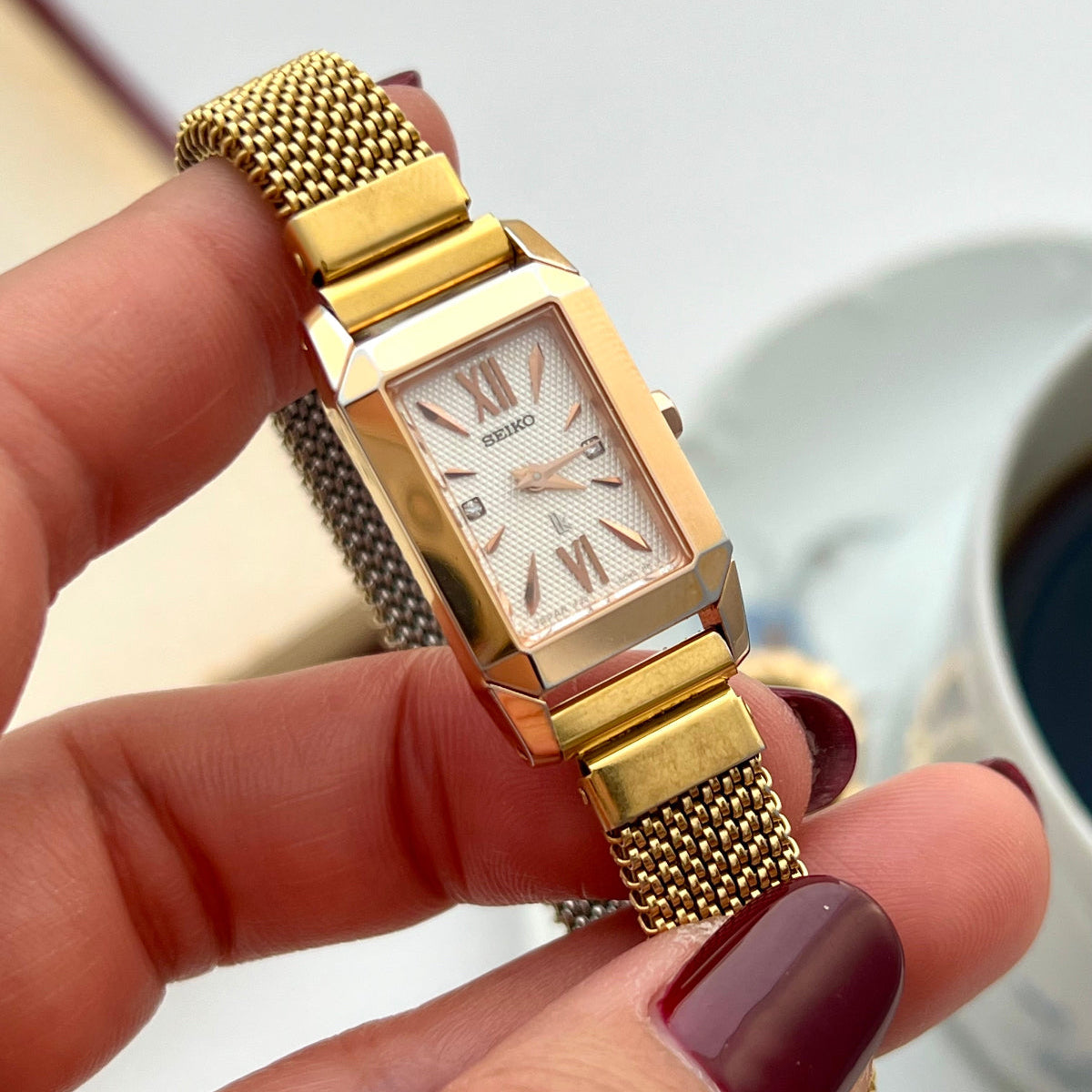 Seiko Gold Women's watch held by a hand with a blurred background