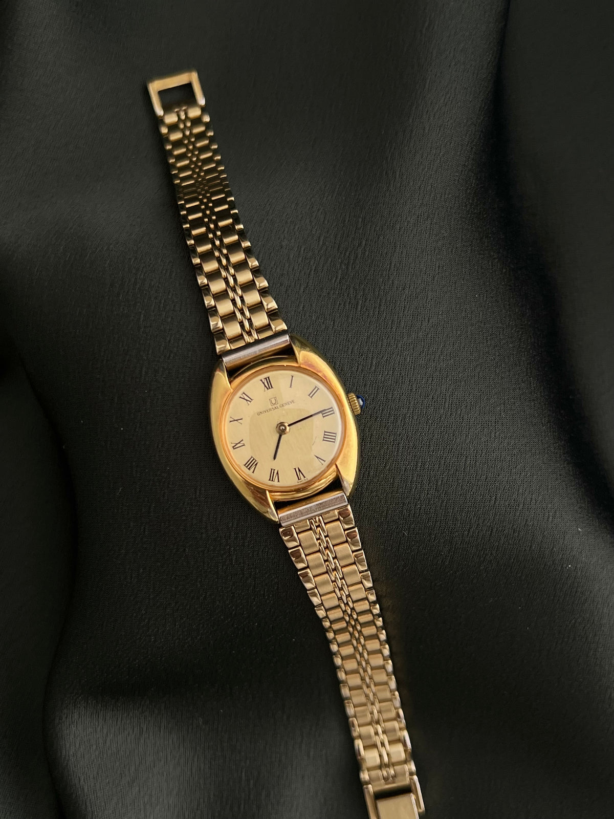 Universal Geneve C Case Roman Dial Gold Watch: full bracelet watch laid flat.