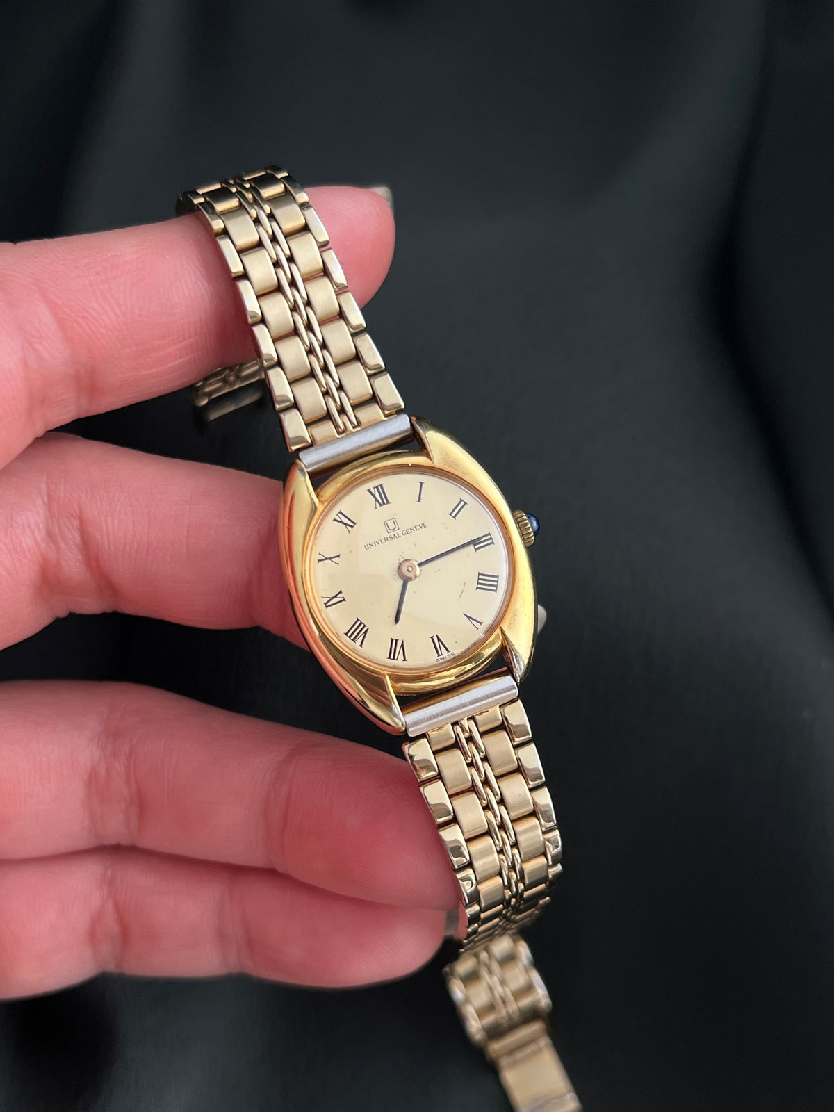 Universal Geneve C Case Roman Dial Gold Watch: watch held in hand.