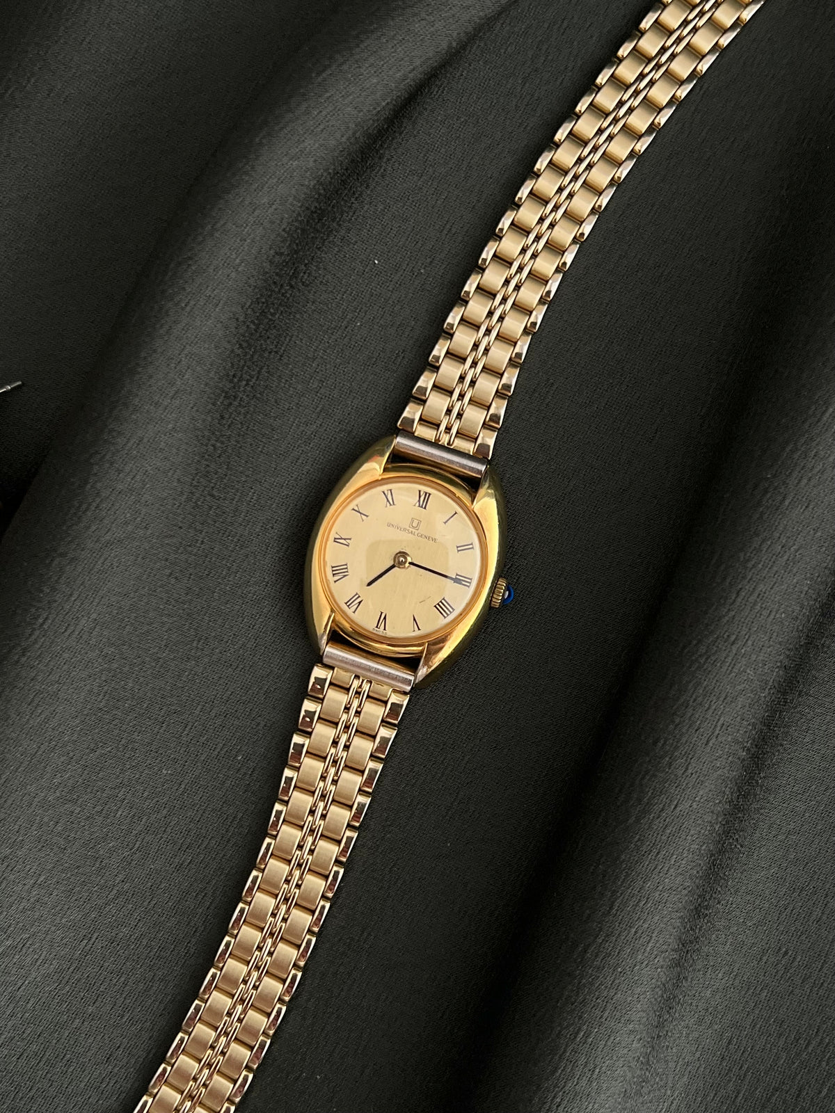 Universal Geneve C Case Roman Dial Gold Watch: full front view beside separate jewellery.