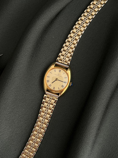 Universal Geneve C Case Roman Dial Gold Watch: full front view beside separate jewellery.