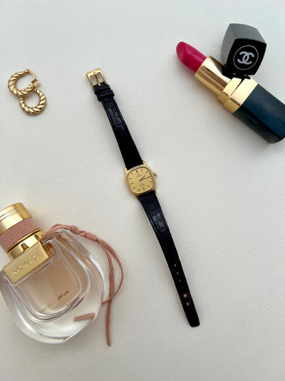 Omega De Ville, Perfume bottle, watch, lipstick, and ring on a light gray background