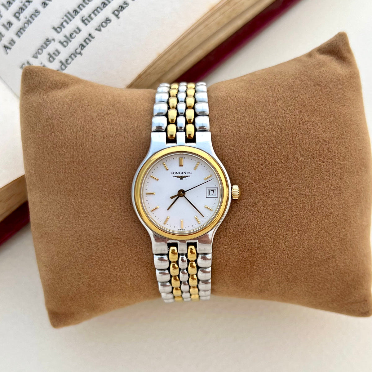 Longines Flagship Two-tone watch on a brown cushion with an open book in the background