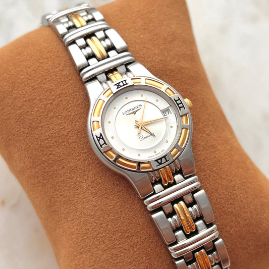 Longines Laureate Silver and gold watch on a brown cushion with a blurred background