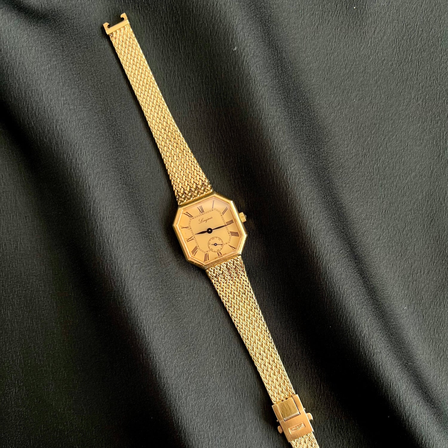 Gold Longines Octo Women's wristwatch on a black fabric background
