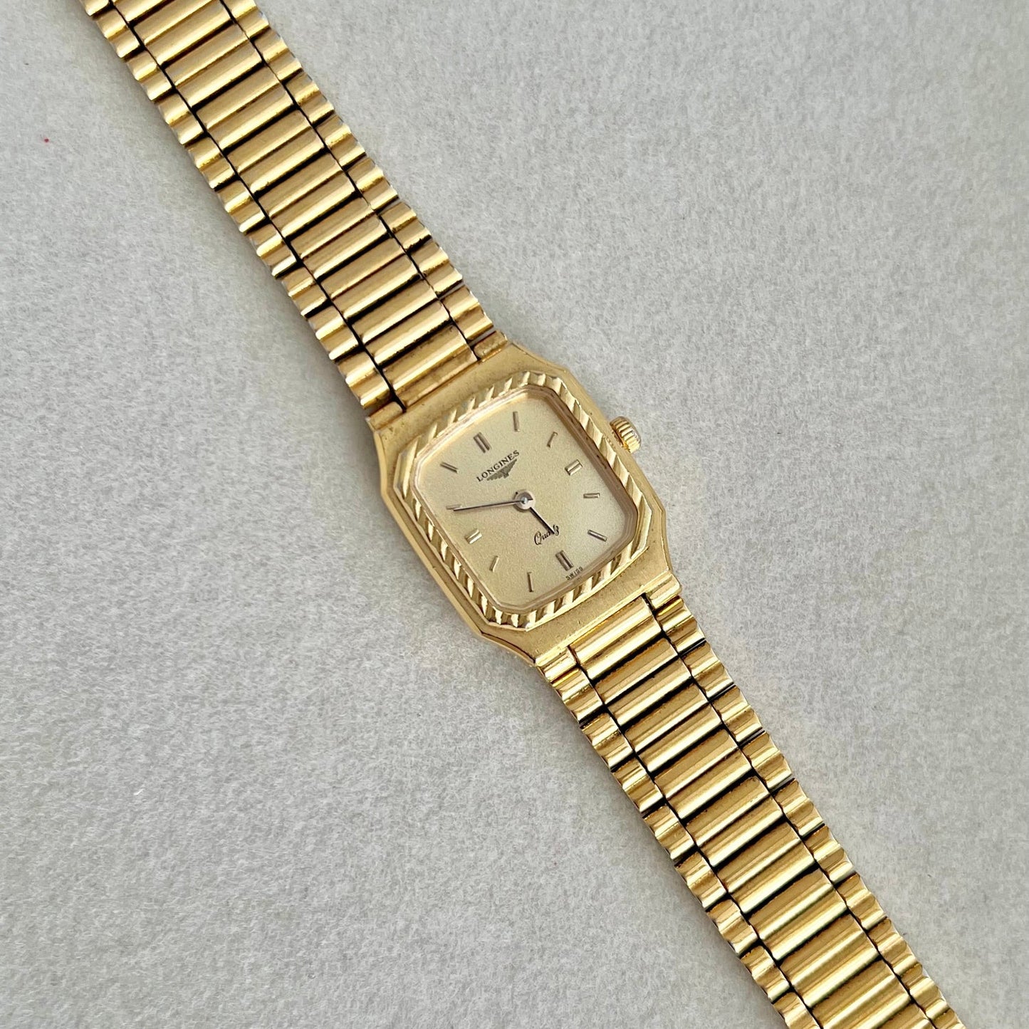Gold Longines Women's Watch with a rope bezel on a light gray background