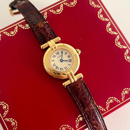 must de Cartier Gold watch with brown leather strap on a red box with gold detailing
