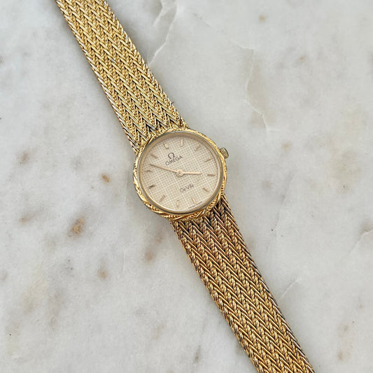 Gold watch with a chain strap on a marble surface
