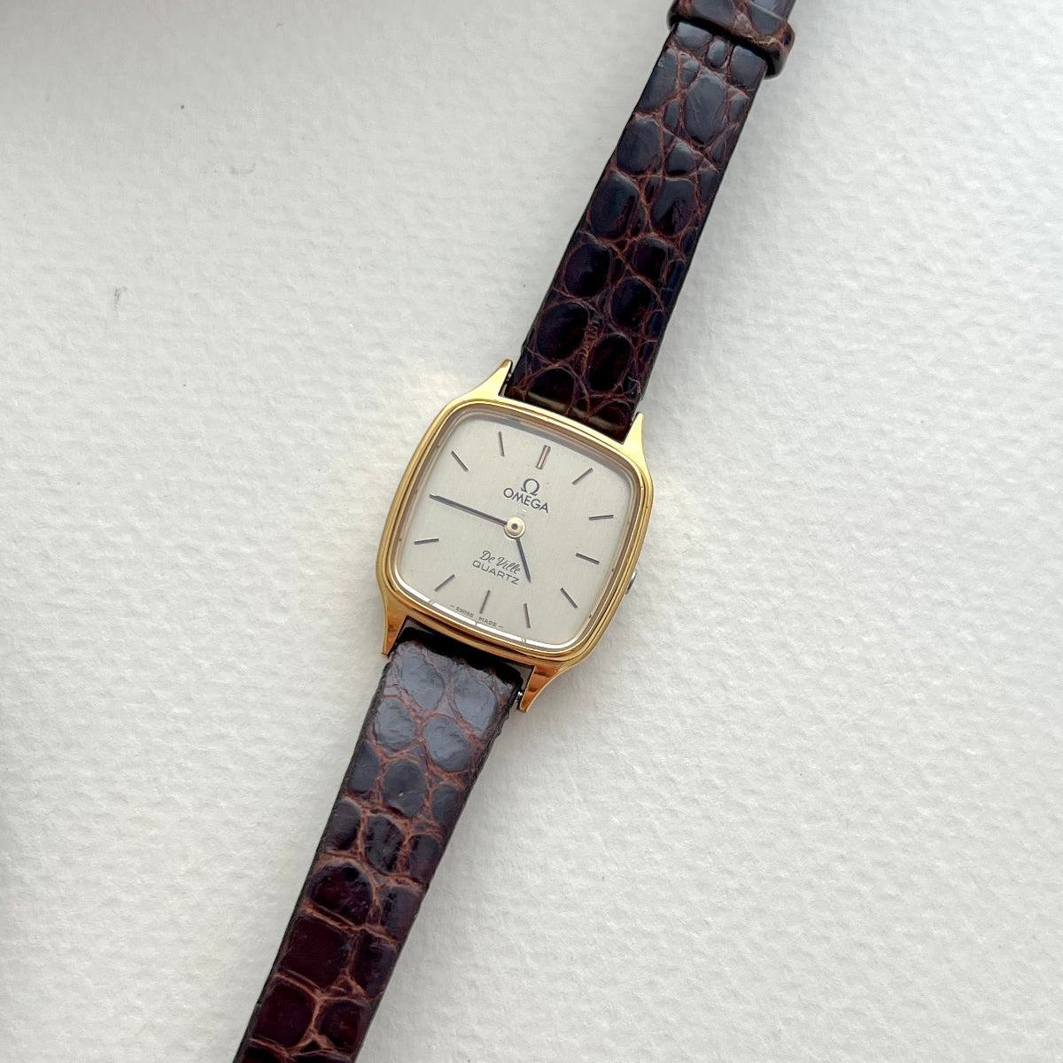 Vintage Omega De Ville watch with brown strap on a white background