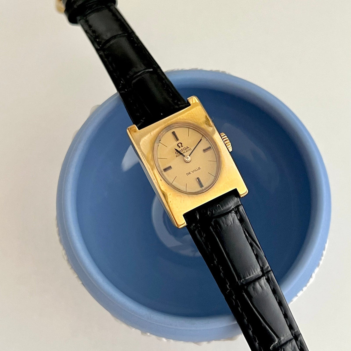 Omega Tank Automatic gold Women's watch with black strap on a white background