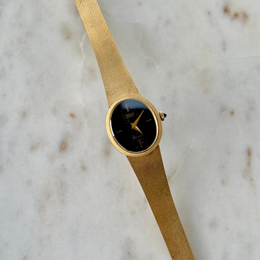 Seiko Exceline Gold watch with a black face on a marble surface