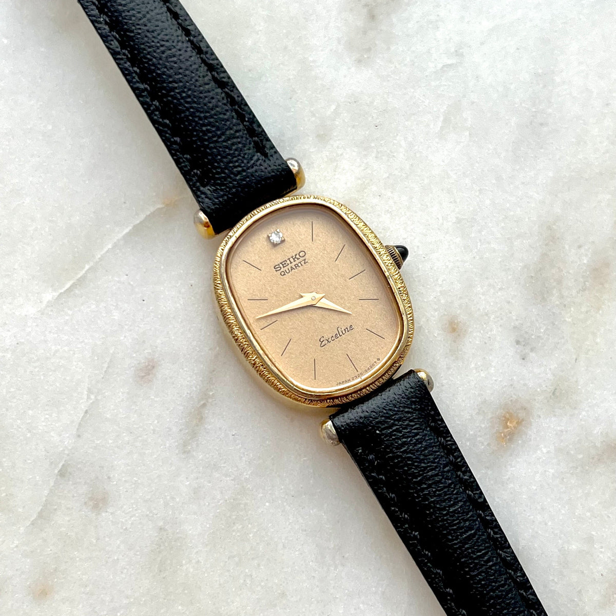 Vintage Seiko Oval Women's watch with black leather strap on a marble surface