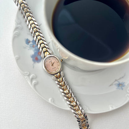 Seiko Exceline Two Tone watch with braided strap on a saucer next to a cup of coffee