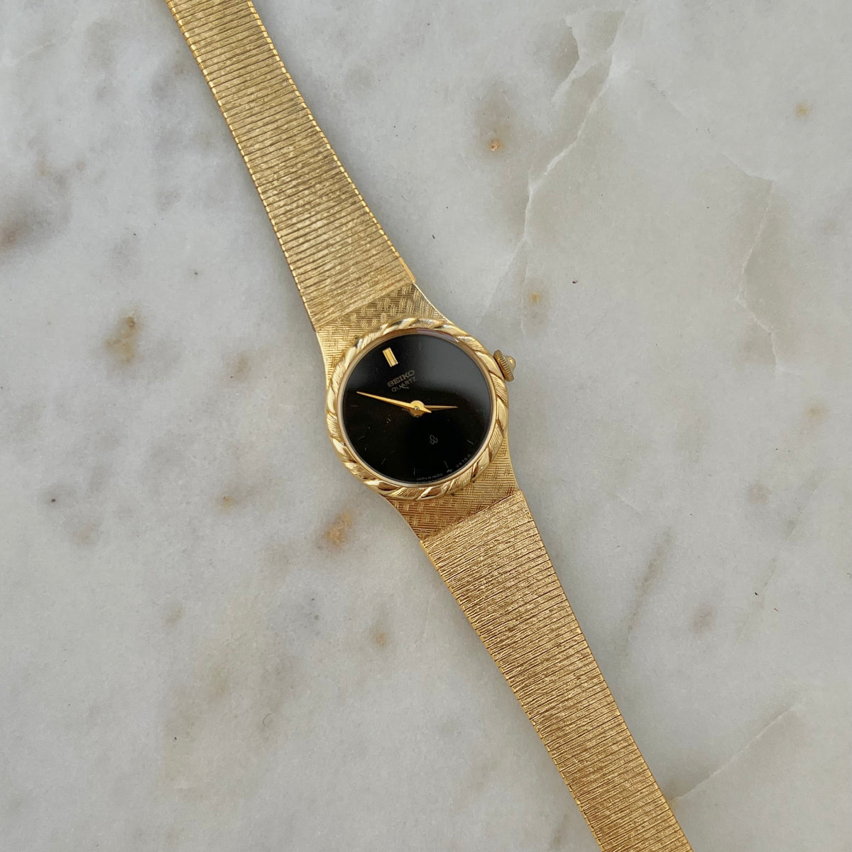 Seiko Gold watch with a black face on a marble surface