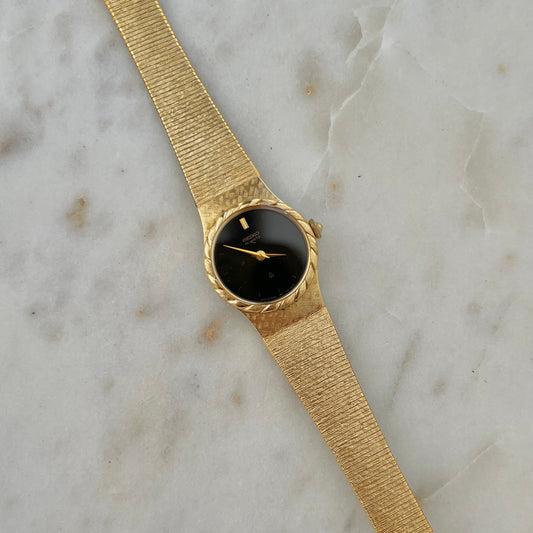 Seiko Gold watch with a black face on a marble surface