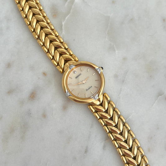 Seiko Gold watch with braided strap on a marble surface