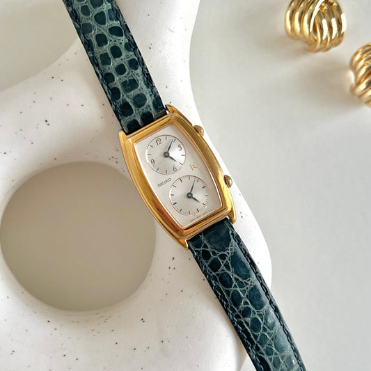 Seiko Noie Dual Dial watch with a green lizard-textured strap on a white surface