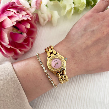 Pink Seiko Woman's watch and bracelet on a wrist with flowers in the background
