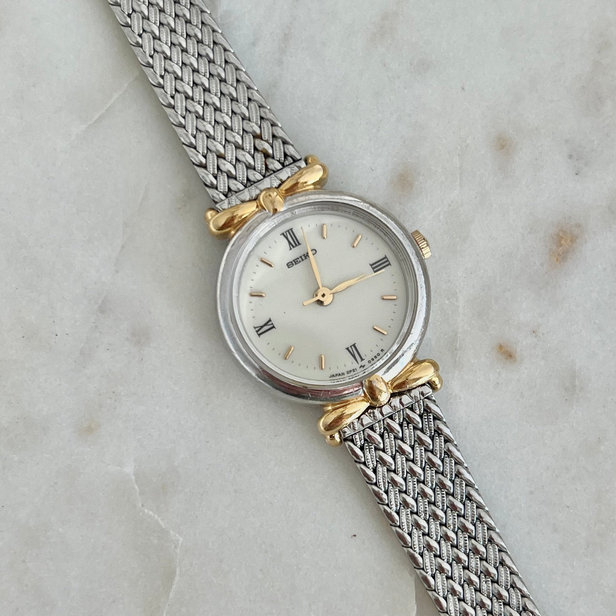 Seiko Ribbon Lug Two Tone Watch: ivory quarter Roman dial and ribbon lugs close.