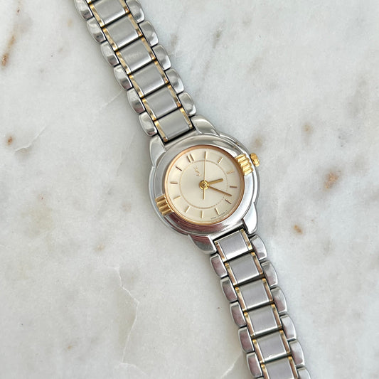 Silver YSL watch with a gold accent on a marble surface