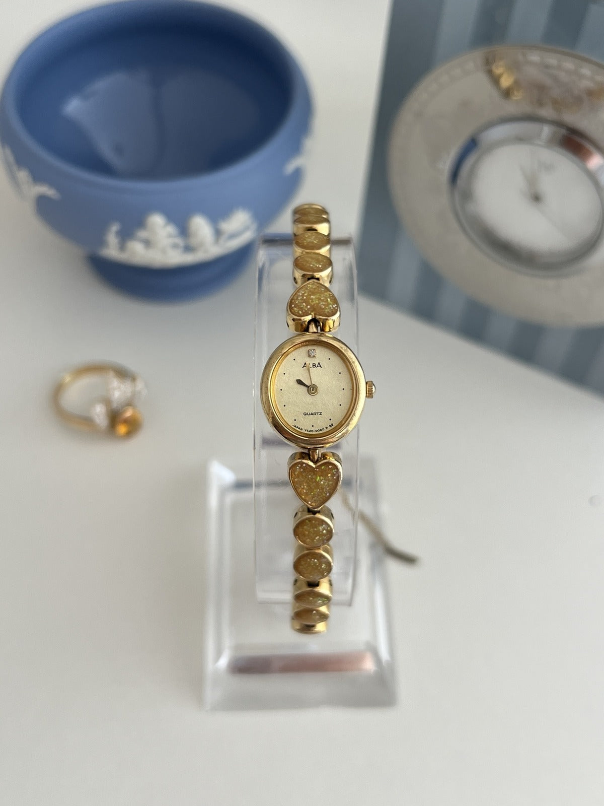 Alba by Seiko women’s cocktail watch with a champagne oval dial and gold tone glitter heart bracelet, shown front on.