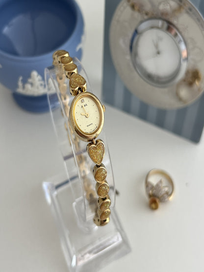 Angled view of the Alba Y520-5020 cocktail watch showing its champagne dial and articulated gold tone heart bracelet.