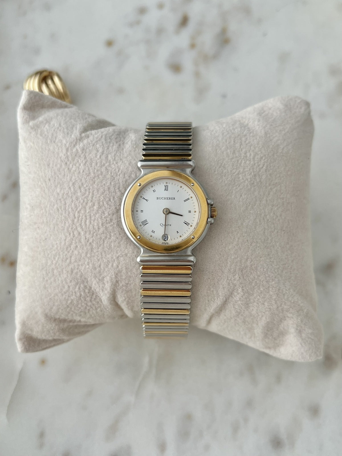 Front view of Bucherer 256.510 two tone women’s watch with ivory Roman numeral dial, date at six and striped bracelet