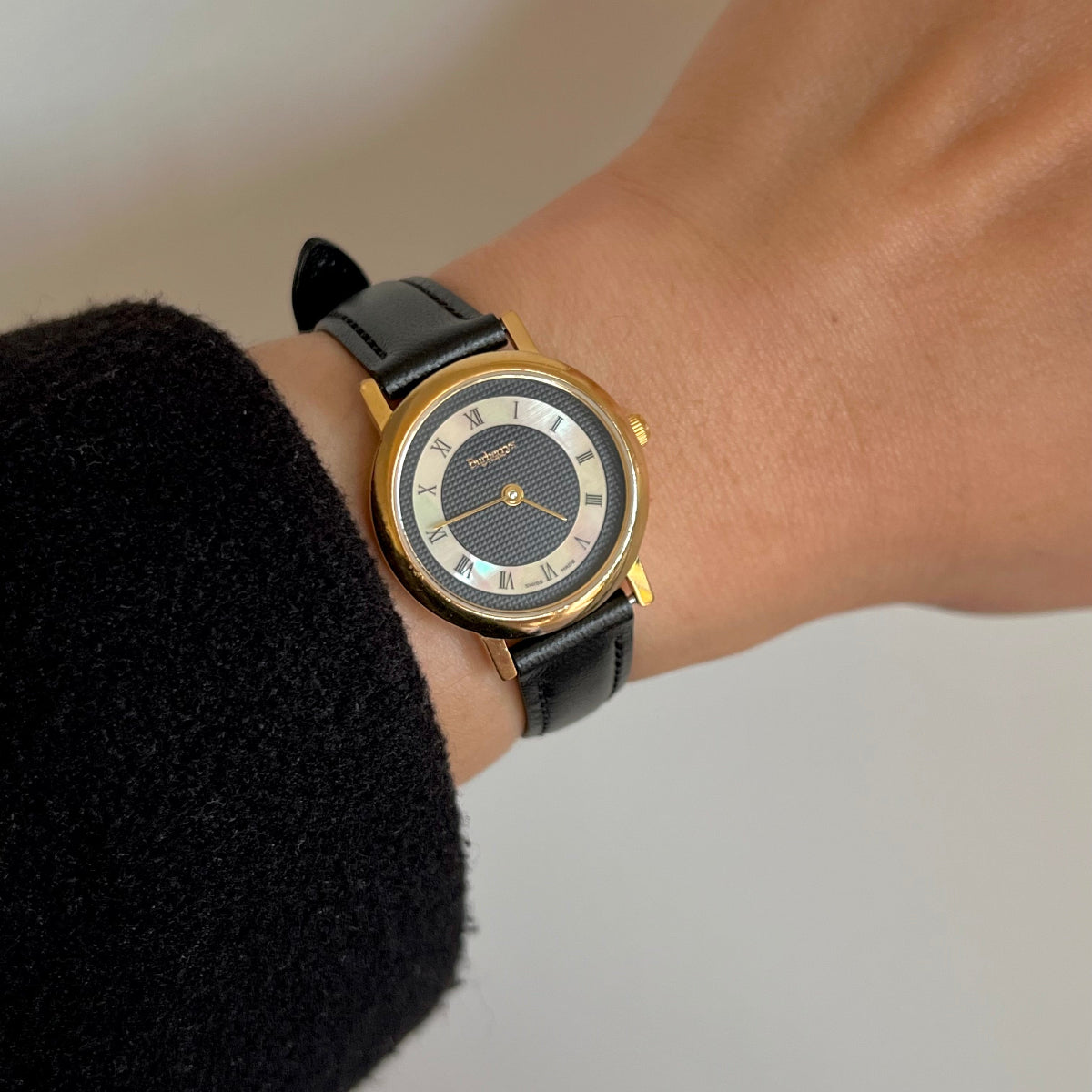 Vintage Burberry women’s watch worn on wrist with black check dial, Roman numeral hour ring, gold tone case and black leather strap