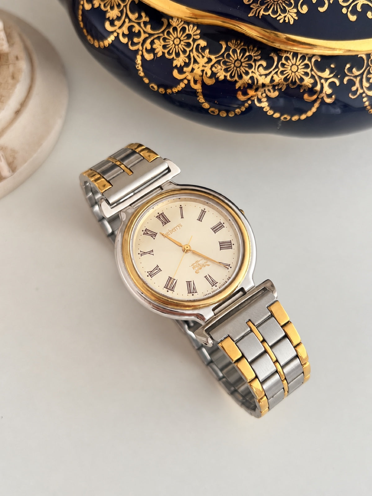 Burberry cream Roman dial watch with brushed silver tone bracelet links and polished gold tone accents.