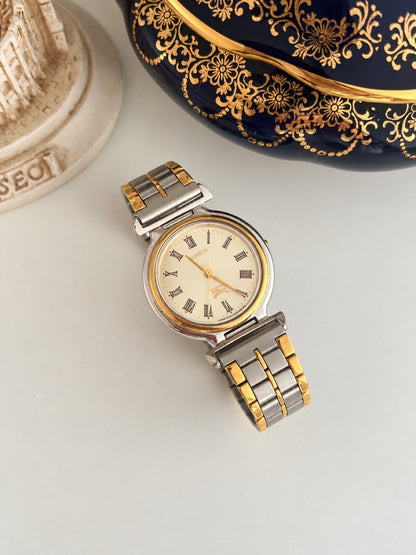 Full view of the Burberry cream Roman dial watch and two tone linked bracelet.