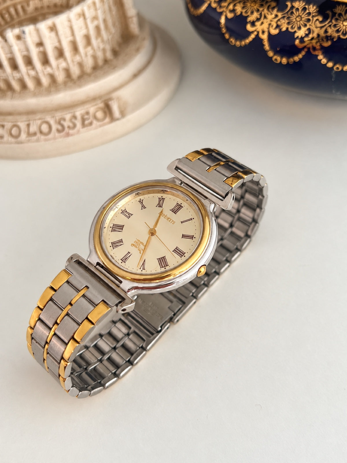 Burberry two tone watch showing the smooth gold tone bezel, silver tone case and bar shaped bracelet connectors.