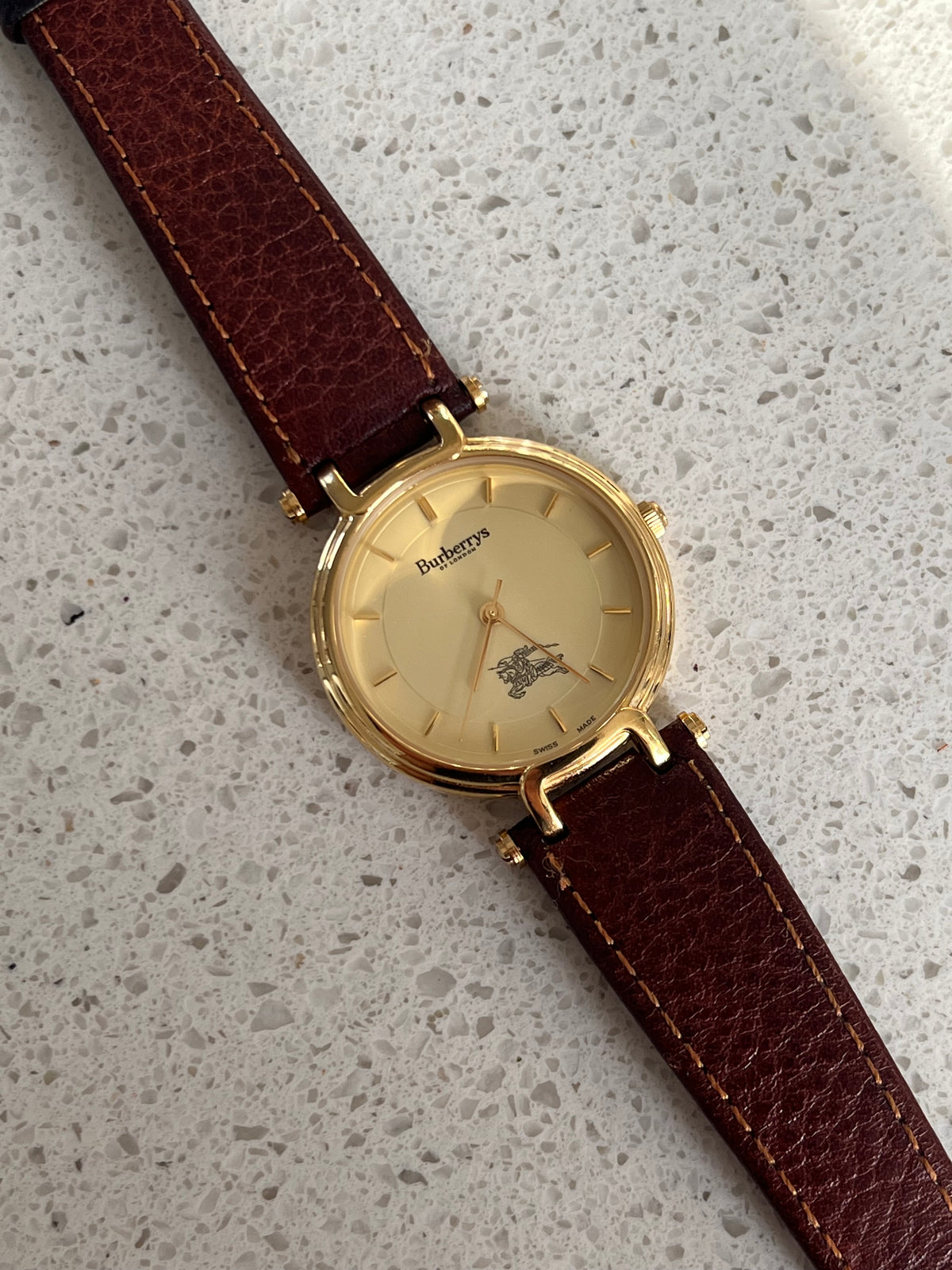 Burberrys gold-tone watch displayed with its included box.