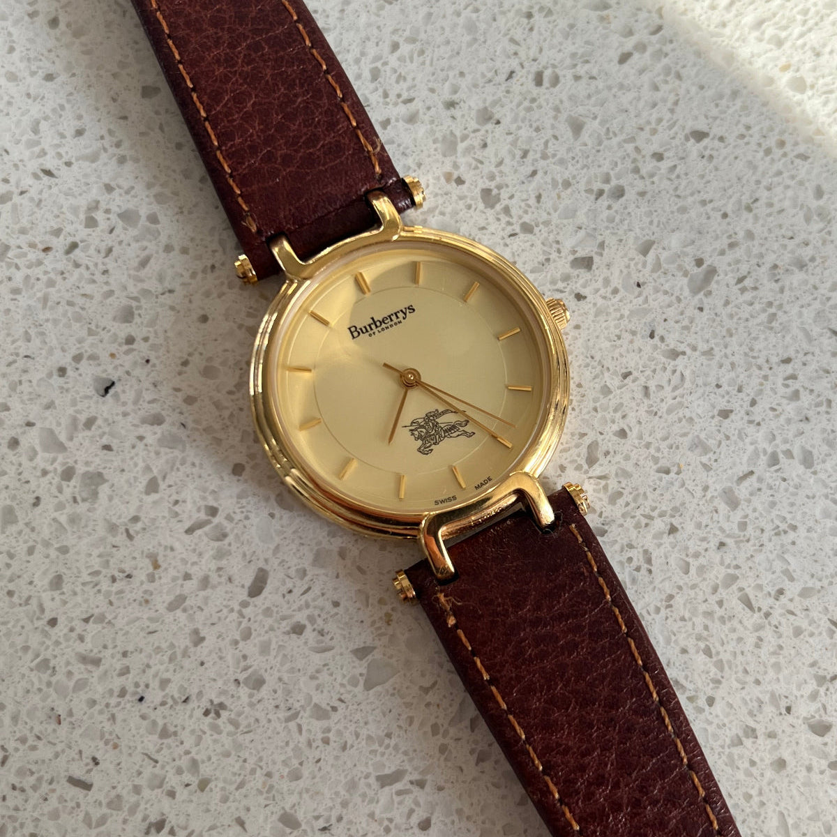 Front view of the Burberrys 32 mm gold-tone round watch with champagne dial and loop lugs.