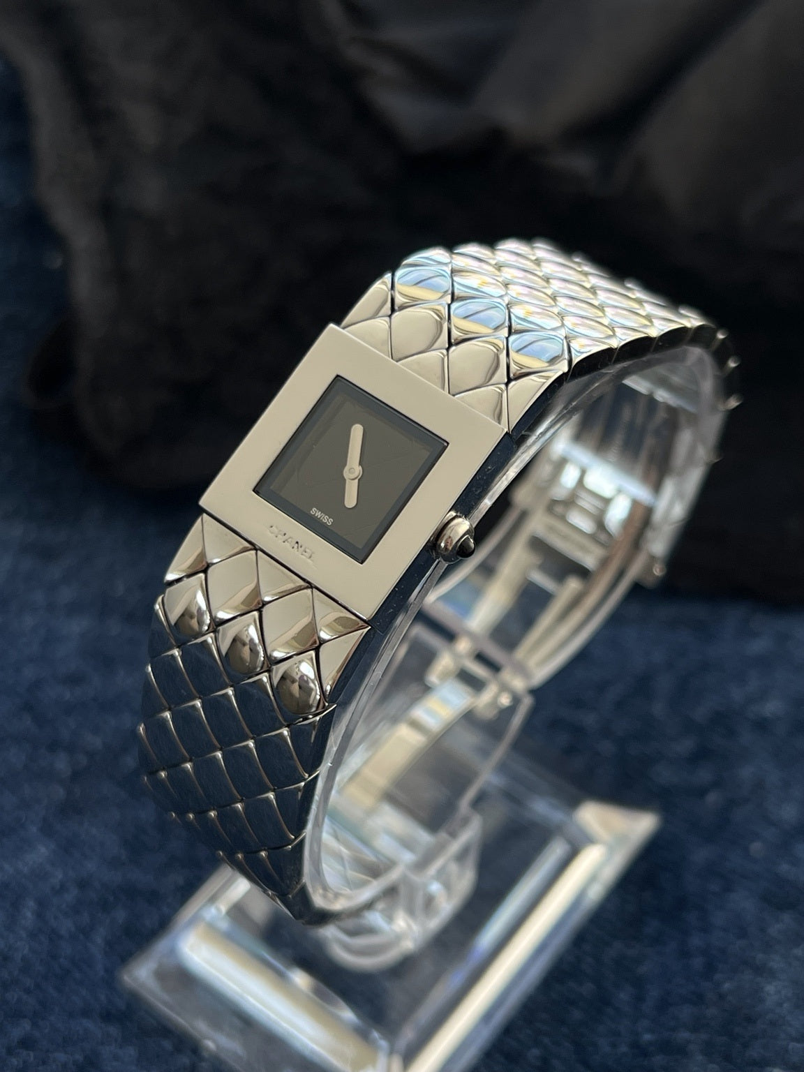 Angled view of the Chanel Matelassé H0009 square black dial, steel frame and black stone crown