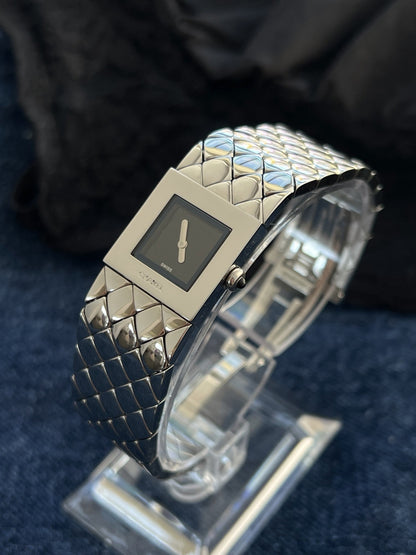 Angled view of the Chanel Matelassé H0009 square black dial, steel frame and black stone crown