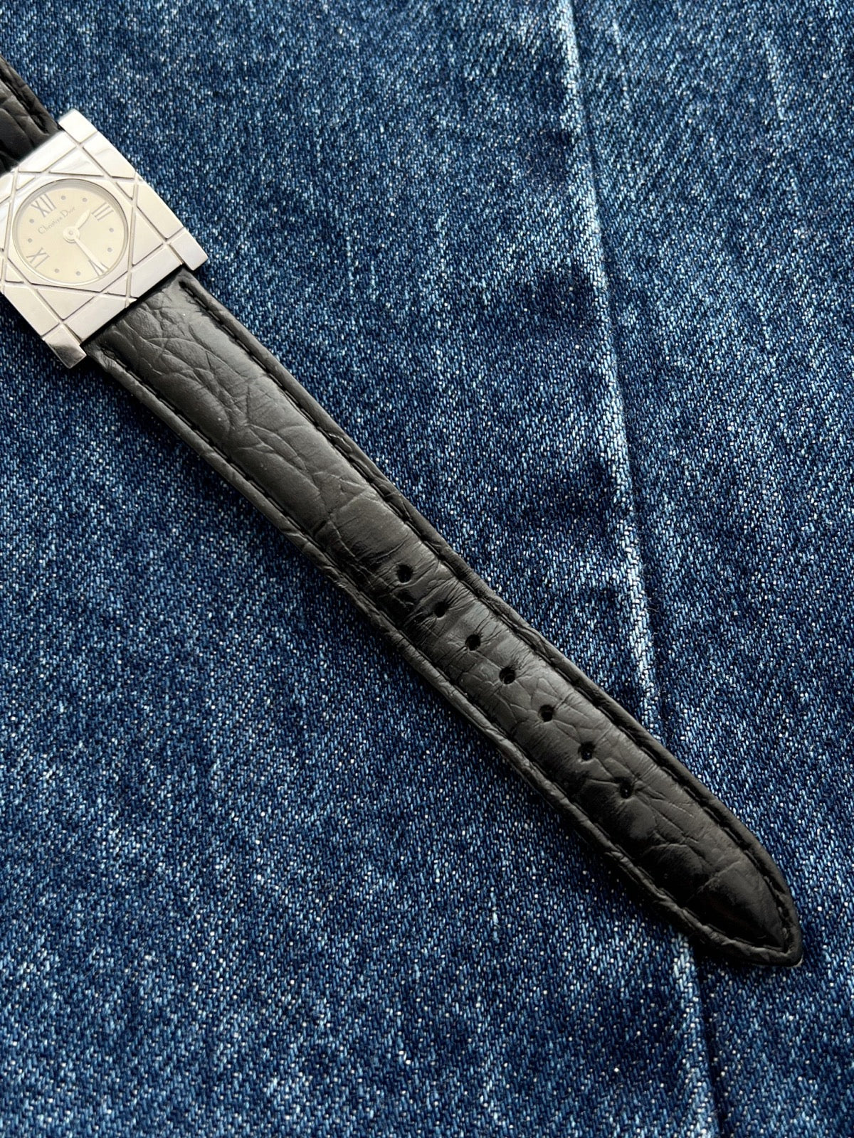 Black textured leather strap and adjustment holes on the Christian Dior Cannage women’s steel watch
