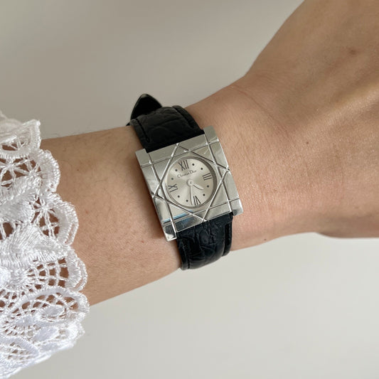 Christian Dior Cannage women’s watch with silver Roman dial, square steel case and black leather strap worn with a white lace sleeve