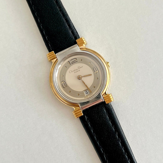 Christian Dior gold tone women’s watch with layered dial, black leather strap, and date window
