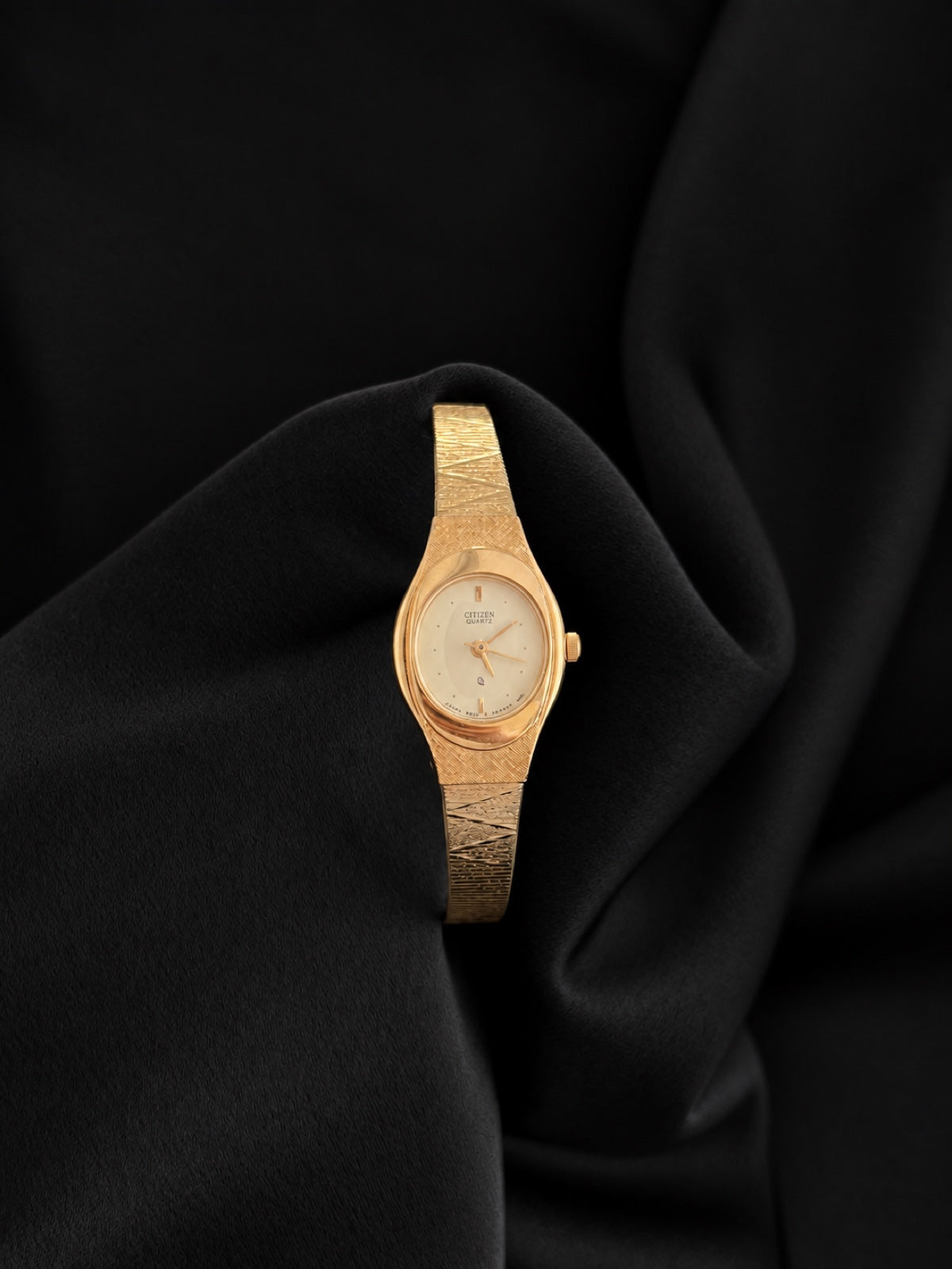 Front view of Citizen 5930-S25350 gold-tone textured bracelet watch with oval champagne dial against black velvet.
