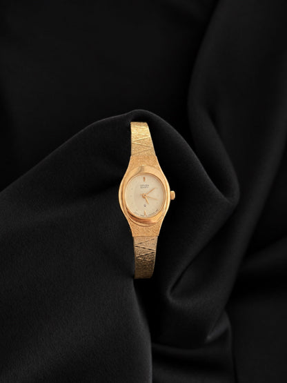 Front view of Citizen 5930-S25350 gold-tone textured bracelet watch with oval champagne dial against black velvet.
