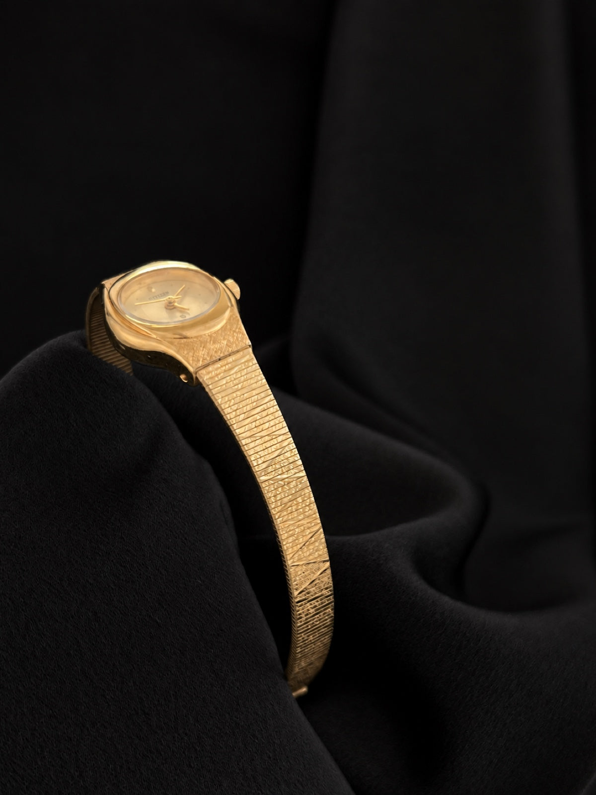 Side profile of Citizen CQ 5930-S25350 showing the oval case and integrated textured gold-tone bracelet.