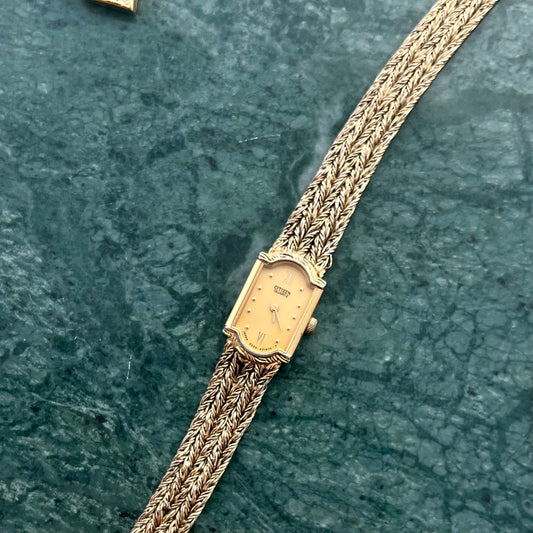 Front view of the Citizen gold tank watch with champagne dial and braided bracelet.