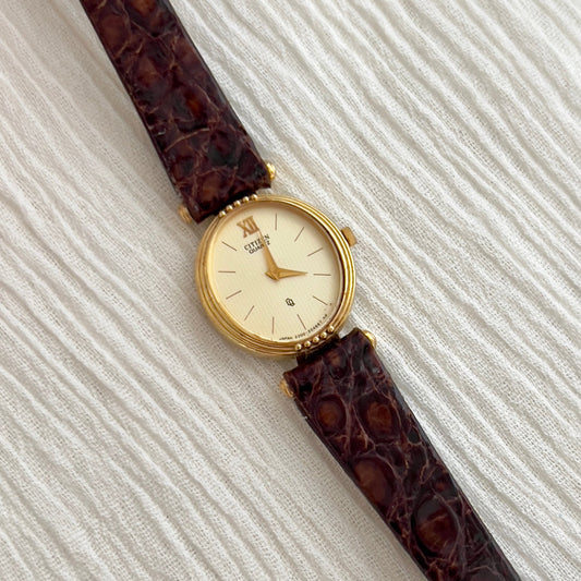 Citizen gold-tone watch with ivory guilloche dial and mesh-style bracelet.