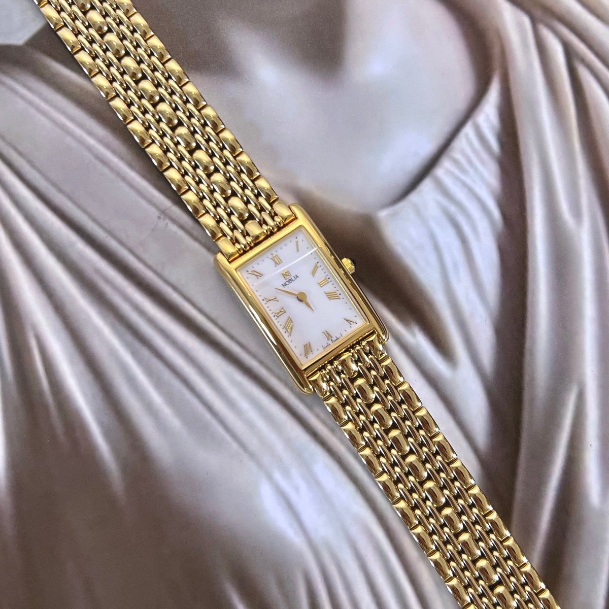 Citizen Noblia women’s watch with Roman numeral dial, small seconds display, rectangular gold tone case and draped jewellery bracelet.